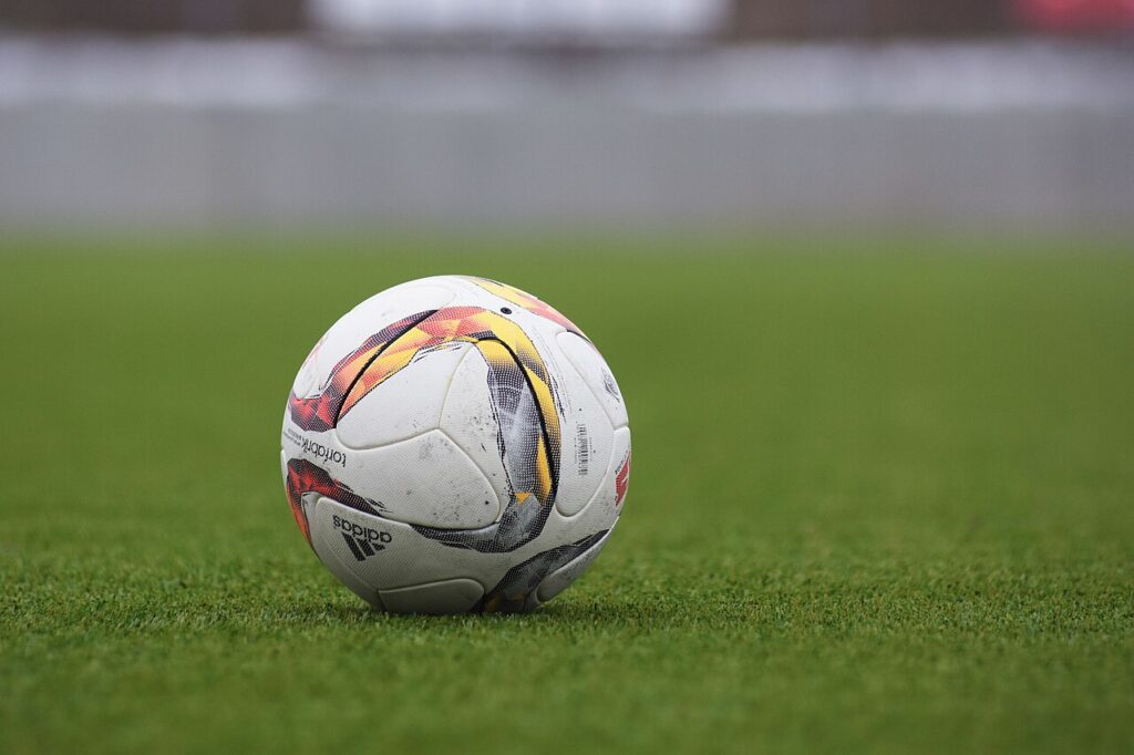 Flat Betting vs Percentage Staking: Which Is Better? 2 Adidas soccer ball on a grass pitch.